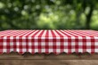 © Muhammad - Red checkered tablecloth on wooden table outdoors.