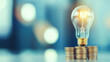© chayantorn - Light bulb on coins symbolizes rising electricity costs and savings