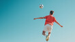 © pattozher - Soccer Player Leaping High: A young athlete leaps towards the sky, showcasing incredible athleticism as he heads the ball with a determined expression.