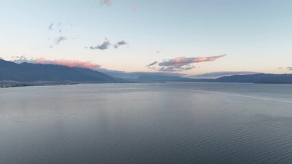 Poster - A serene 4K aerial view of Erhai Lake in Dali, Yunnan, China.  Pink hues paint the distant mountains at sunset.