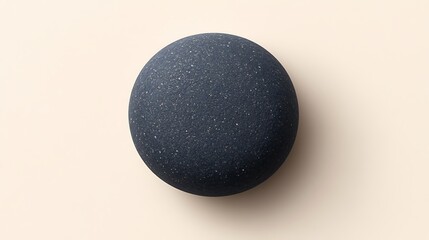 Poster - Dark gray, round stone on beige background.