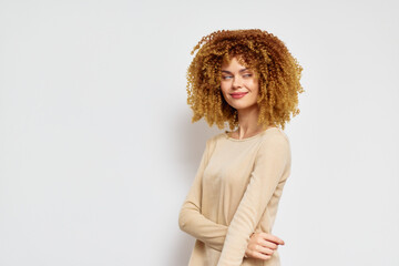 Wall Mural - Smiling woman with curly hair in a beige top against a white background, exuding confidence and joy Perfect for concepts of beauty and self expression