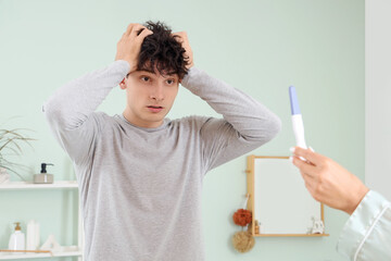 Wall Mural - Shocked young man and his girlfriend with pregnancy test in bathroom