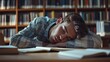 © Thuntaree - Exhausted Student Sleeping on a Library Table Surrounded by Books