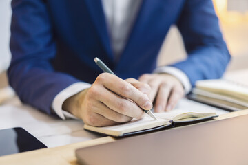 Poster - Close-up capture of a man's hand as he writes in a notepad, with an out-of-focus background