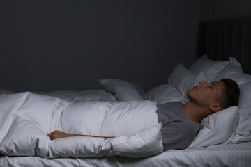 Wall Mural - Young man sleeping in soft bed at night