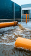 © Olivia - Industrial Flood Drainage Orange Pipes Pumping Water near Factory.