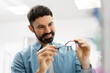 © Maria Vitkovska - Happy, smiling bearded man choosing eyeglasses in optical store