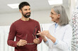 © Maria Vitkovska - Senior female optician helping a male customer choosing eyeglasses in optical store