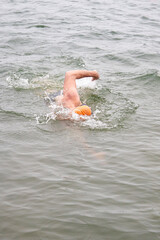 Wall Mural - A man is swimming in the ocean wearing an orange hat