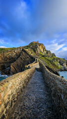 Gaztelugatxe, a small island in the Basque Country of Spain. A stone pathway leads up to the chapel atop the island, surrounded by dramatic cliffs and ocean views.