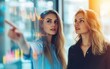 © Surachetsh - Two focused businesswomen analyze vibrant data visuals on a futuristic display, embodying innovation and collaborative decision making.