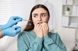© New Africa - Dental phobia. Dentist working with scared woman in clinic, closeup