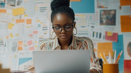 Wall Mural - Focused Black Businesswoman Working on Laptop in Creative Office Space