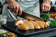 © Віталій Б. - Chef skillfully slices grilled chicken breast garnished with fresh vegetables in a modern kitchen