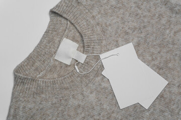 a beige wool sweater with a round neckline, featuring an empty inner label and two blank tags attach