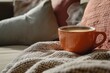 © shafiyyah - Steaming coffee in orange mug on cozy knit blanket. (1)