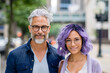 © SuzeO - urban couple fashion, a chic middle-aged couple strolling in the city the man has dark blue hair and a beard, the woman rocks purple waves