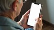 © Helga P-A. - An older person is holding a smartphone with a blank white screen. Concept of senior technology. Mock up