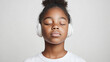© Ari - Afro girl with closed eyes listening to music through modern headphones