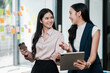 © Satori Studio - Two professional women discussing ideas in a bright office space, surrounded by colorful sticky notes.