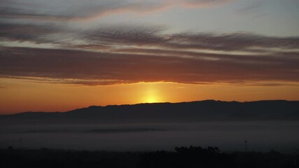 Wall Mural - time lapse orange sunrise behind a mountain with clouds.