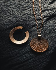 Poster - A close-up of two pieces of jewelry, a pendant and a ring, on a textured dark surface.