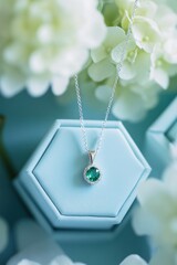 Poster - A delicate silver necklace with a green gemstone, displayed on a soft blue background.