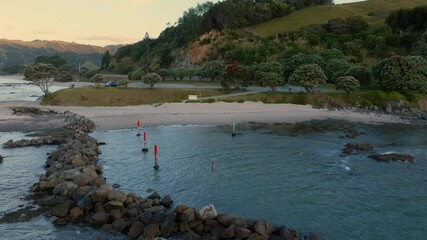 Wall Mural - Coastal scenery at sunset. Calm water, rocks, and markers. A tranquil beach scene. , KUAOTUNU, COROMANDEL PENINSULA, NEW ZEALAND