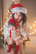 © oatawa - Happy asian mother picks up baby daughter looking at camera near Christmas tree at home on Christmas holiday