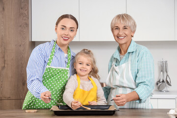 Wall Mural - Little girl with her mom and granny preparing cookies in kitchen