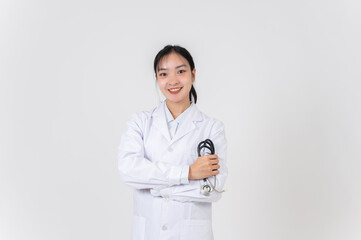 Smiling Asian female doctor in a uniform holding a stethoscope, standing against a white background.