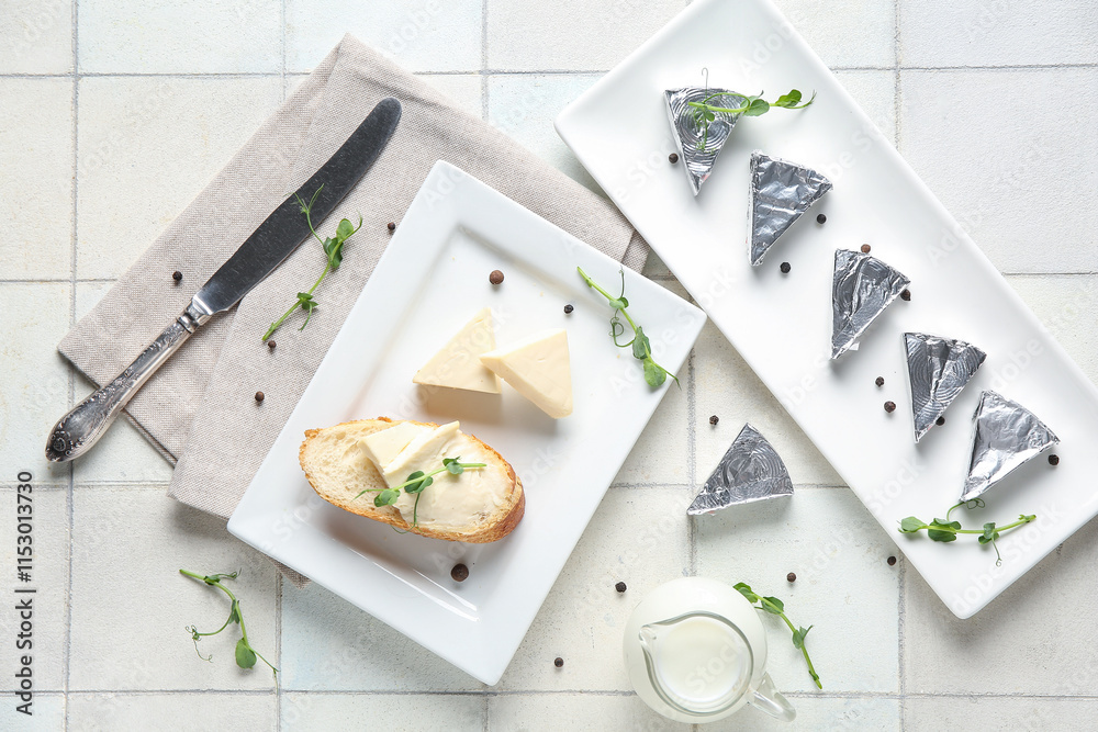 Composition with triangles of tasty processed cheese, bread, micro green and spices on light tile background
