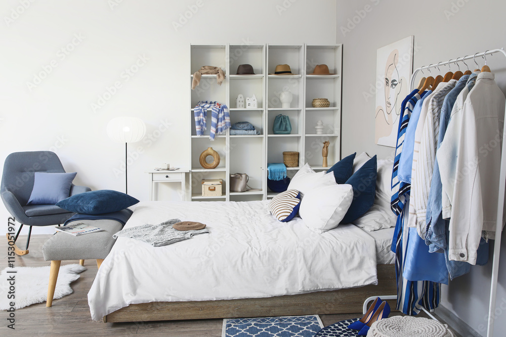 Interior of stylish bedroom with clothes rack and shelving unit