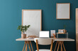 © Pixel-Shot - Workplace with laptop and blank posters near blue wall in room