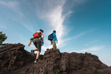 Two hikers exploring volcanic terrain under a clear blue sky - couple trekking in the nature