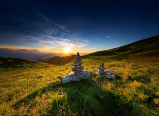 Poster - Serene sunset over rolling hills, capped with vibrant blue skies.  Two carefully balanced stone cairns sit peacefully in the foreground, bathed in golden light.  A tranquil landscape of nature's beaut