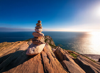 Poster - Serene sunset over a vast ocean, a carefully balanced rock cairn perched atop a cliff, symbolizing peace and mindfulness.  The golden hour light bathes the scene in warmth.