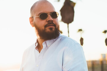Fototapete - serious hipster guy looking away standing outdoors with smartphone in hands for sending online text 