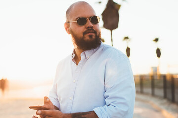 Fototapete - serious hipster guy looking away standing outdoors with smartphone in hands for sending online text 