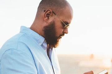 Fototapete - Concentrated hipster guy read news from browsed website on smartphone spending free time in city outdoors, handsome male using modern cellular and 4G connection for chatting in social networks online