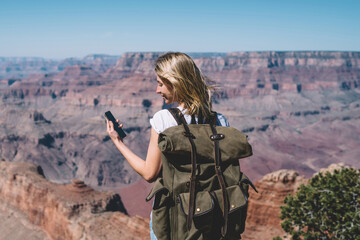 Wall Mural - young hipster girl reading message on smartphone standing on mountains viewpoint using roaming, fema