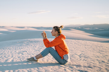 Wall Mural - female traveler making pictures of beautiful desert landscape with white dunes using telephone camer