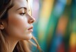 © Pod - A young Caucasian woman with long brown hair, eyes closed, face in profile against a blurred colorful abstract background