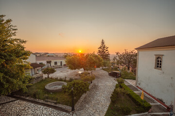 Wall Mural - Sunset over a charming village square with stone pathways and traditional buildings.