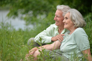 Canvas Print - Portrait of senior couple sitting on the grass in the park