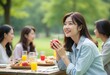 © Vibudhaart - A group of young women enjoying a picnic lunch outdoors, one woman is smiling and holding a glass of juice.