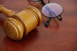 © Valerii Evlakhov - Close-up of wooden gavel and eyeglasses. Court and laws concept.