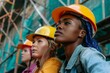 © juliars - Three women wearing hard hats and looking up while standing in building site