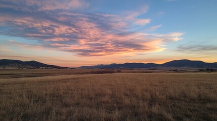 Aufkleber - Scenic landscape photograph capturing vibrant sunset over fields and distant mountains with dramatic clouds in the sky.